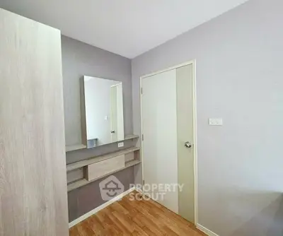 Modern bedroom with wooden flooring and sleek wall-mounted mirror