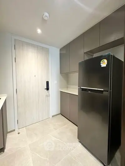 Modern kitchen with sleek cabinetry and stainless steel fridge in a compact layout.