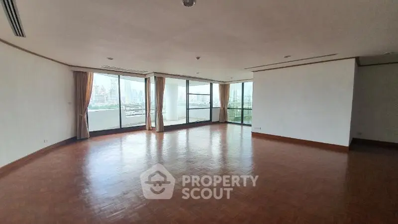 Spacious corner unit living room with panoramic city views and large windows.