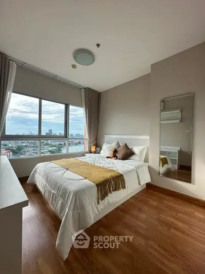 Spacious bedroom with city view, wooden flooring, and modern decor in a high-rise apartment.