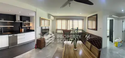 Modern open-plan living room with kitchen, featuring stylish furniture and natural light.