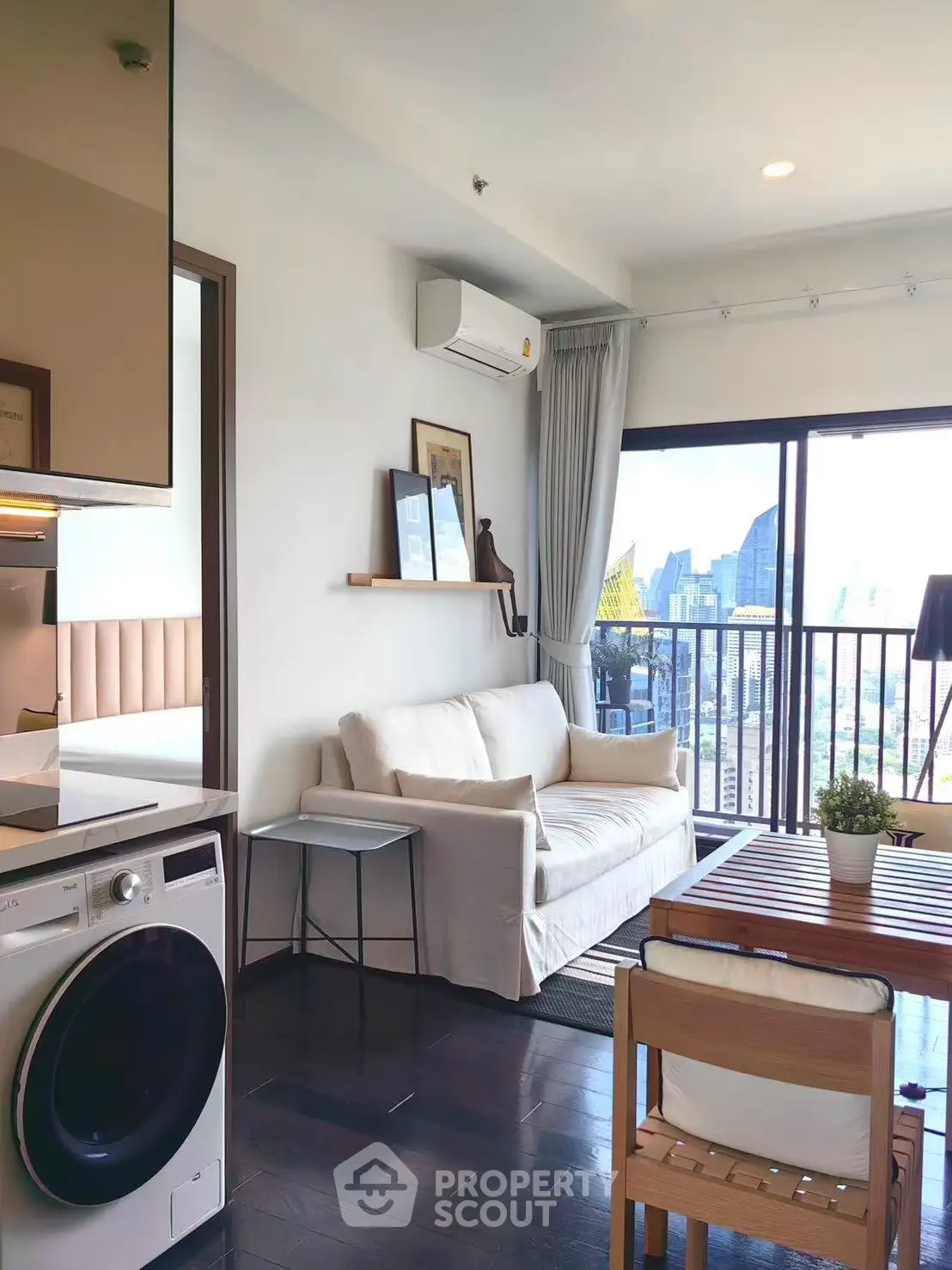 Modern living room with city view, featuring a cozy sofa, dining table, and in-unit washing machine.