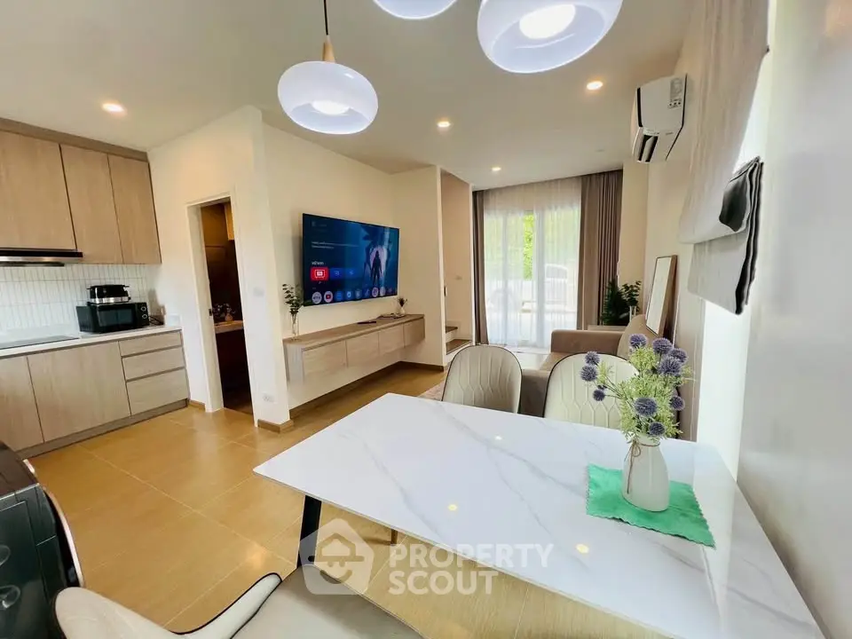 Modern open-layout living room with stylish kitchen and dining area, featuring elegant lighting and contemporary decor.
