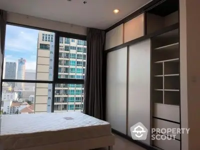 Modern bedroom with city view and built-in wardrobe in high-rise apartment