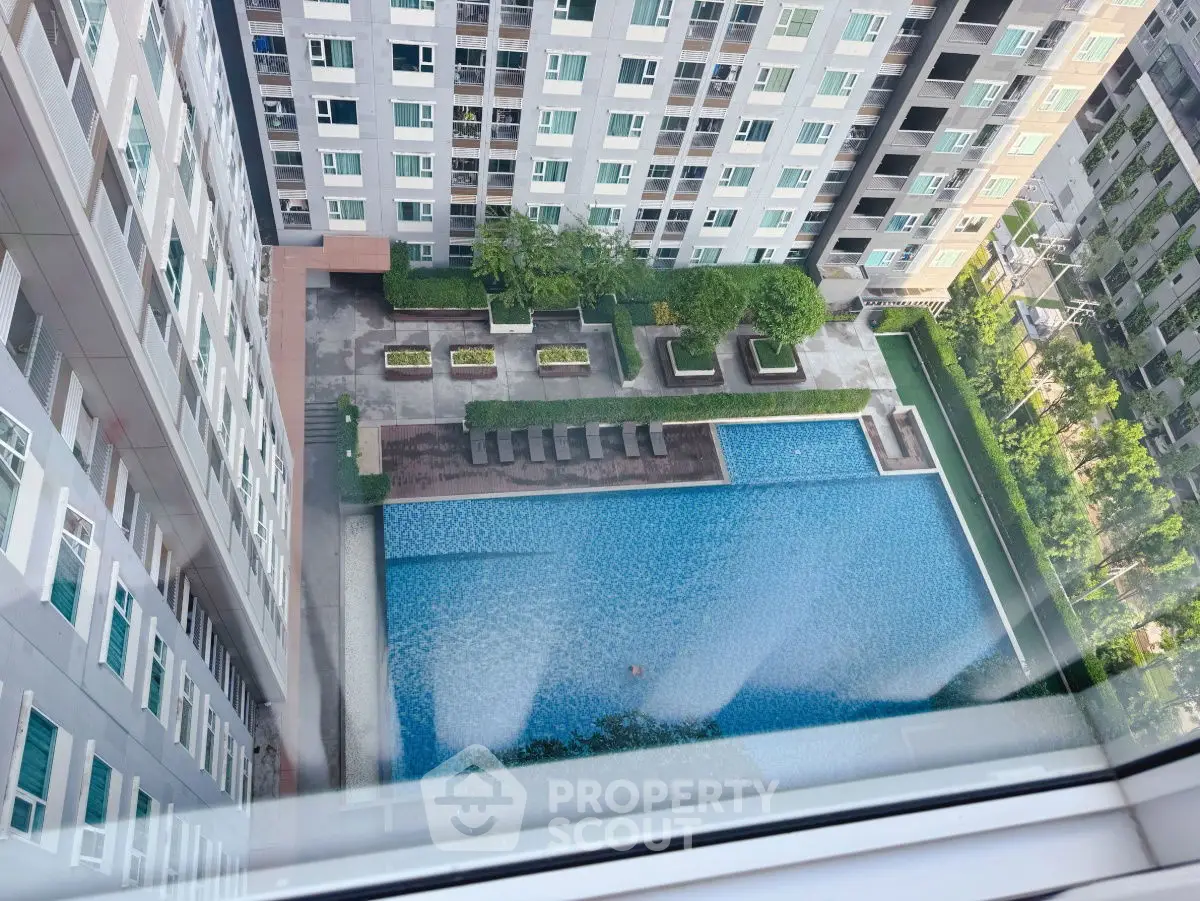 Stunning aerial view of modern apartment complex with large swimming pool and lush greenery.