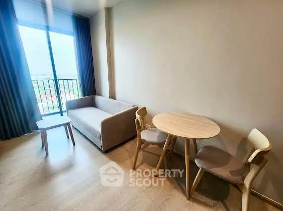 Modern living room with cozy sofa and dining set, featuring a large window with a view.