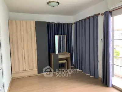 Spacious bedroom with modern wardrobe and vanity, featuring floor-to-ceiling curtains and natural light.