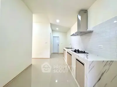 Sleek modern kitchen with marble countertops and gas stove in a spacious open layout.