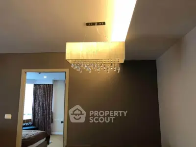 Modern living room with elegant chandelier and view into cozy bedroom