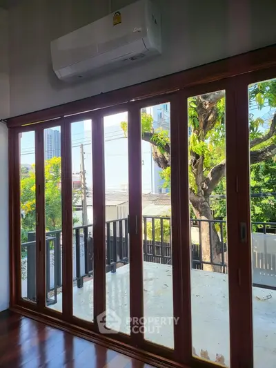 Spacious balcony with wooden sliding doors and lush green view