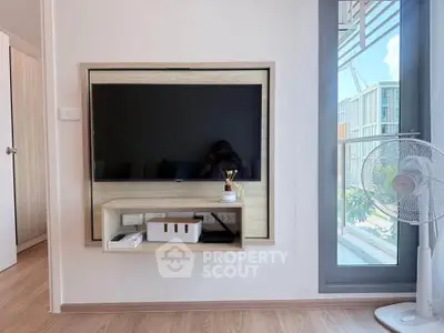 Modern living room with wall-mounted TV and large window offering natural light