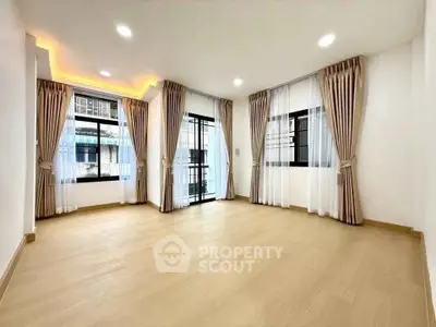 Spacious corner unit with large windows and elegant curtains in a bright living room.