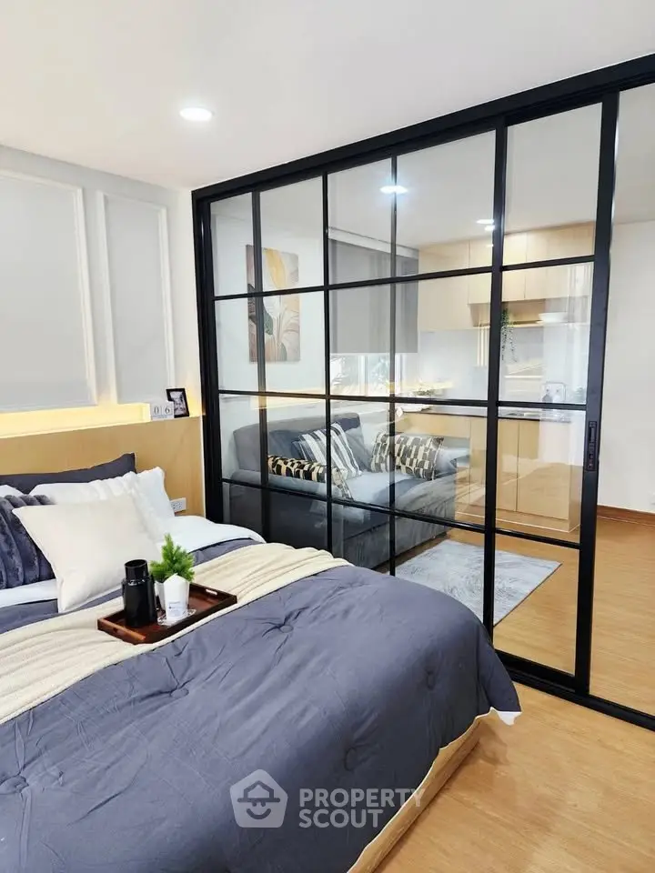 Modern bedroom with sliding glass doors leading to a stylish living area and kitchen.