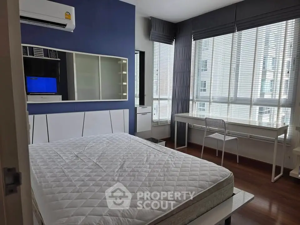 Modern bedroom with large windows and stylish decor in a high-rise apartment.
