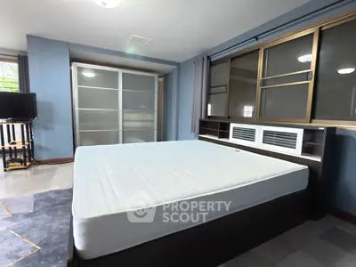 Spacious bedroom with large windows and modern sliding closet doors.