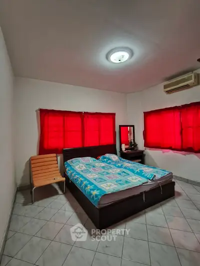 Cozy bedroom with vibrant red curtains and modern furnishings, perfect for relaxation.
