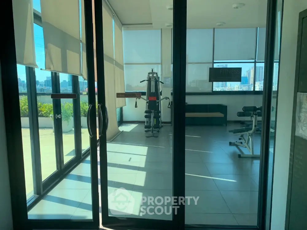 Modern gym with city view and fitness equipment in a high-rise building.