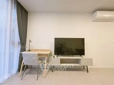 Modern living room with sleek TV setup and cozy workspace by large window.