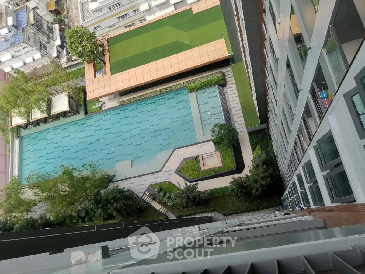 Stunning aerial view of modern apartment complex with luxurious swimming pool and lush greenery.