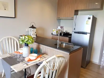 Modern kitchen with sleek design and dining area, featuring stainless steel fridge and elegant decor.