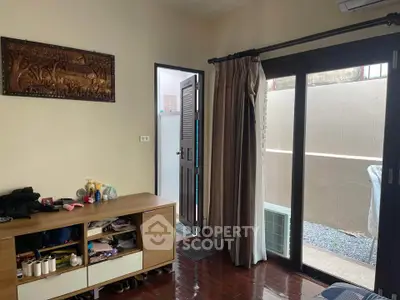 Cozy bedroom with wooden flooring and sliding glass doors leading to a private patio.