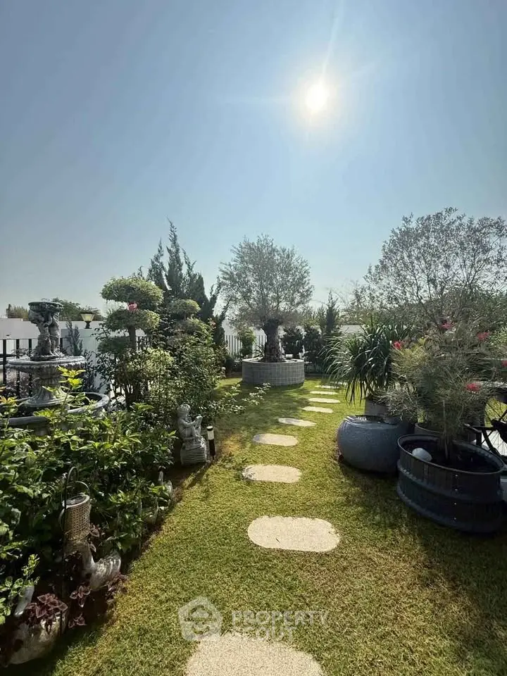 Stunning rooftop garden with lush greenery and serene pathway under a bright sun.