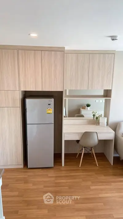 Modern apartment interior with built-in wooden cabinets and a sleek fridge, featuring a cozy study nook.