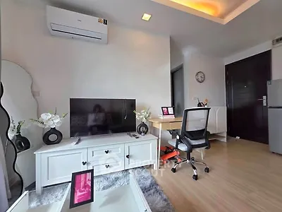Modern living room with stylish decor, featuring a TV unit, desk, and air conditioning.