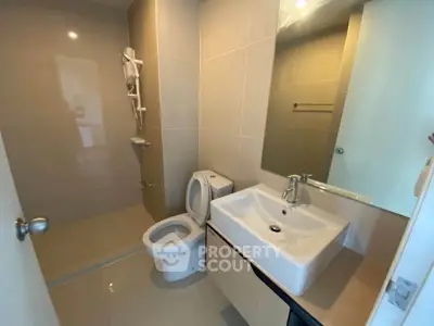Modern bathroom with sleek fixtures and spacious shower area in a contemporary apartment.
