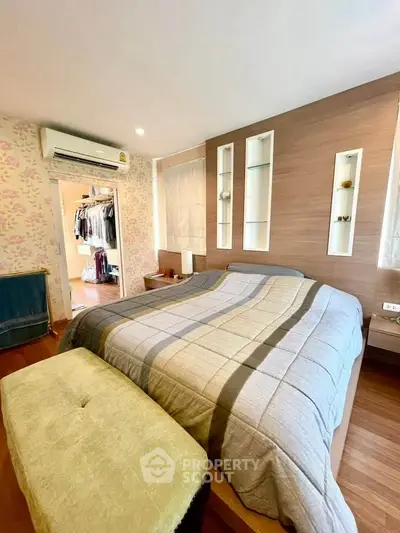 Cozy bedroom with modern decor and walk-in closet, featuring stylish bedding and wooden accents.