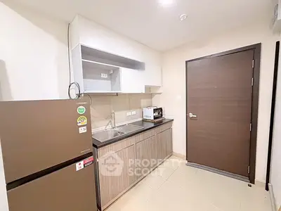 Modern kitchen with sleek cabinetry and stainless steel appliances in a cozy apartment.