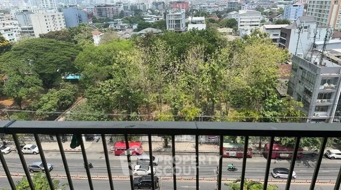 Stunning city view from high-rise balcony overlooking lush greenery and urban landscape.