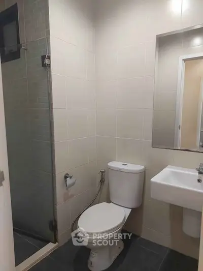 Modern bathroom with sleek fixtures and glass shower enclosure in a contemporary apartment.