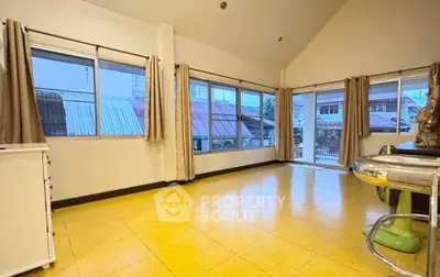 Spacious living room with large windows and vibrant yellow flooring, offering abundant natural light.