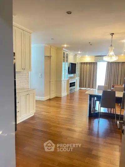 Spacious open-plan living and dining area with elegant chandelier and hardwood floors.