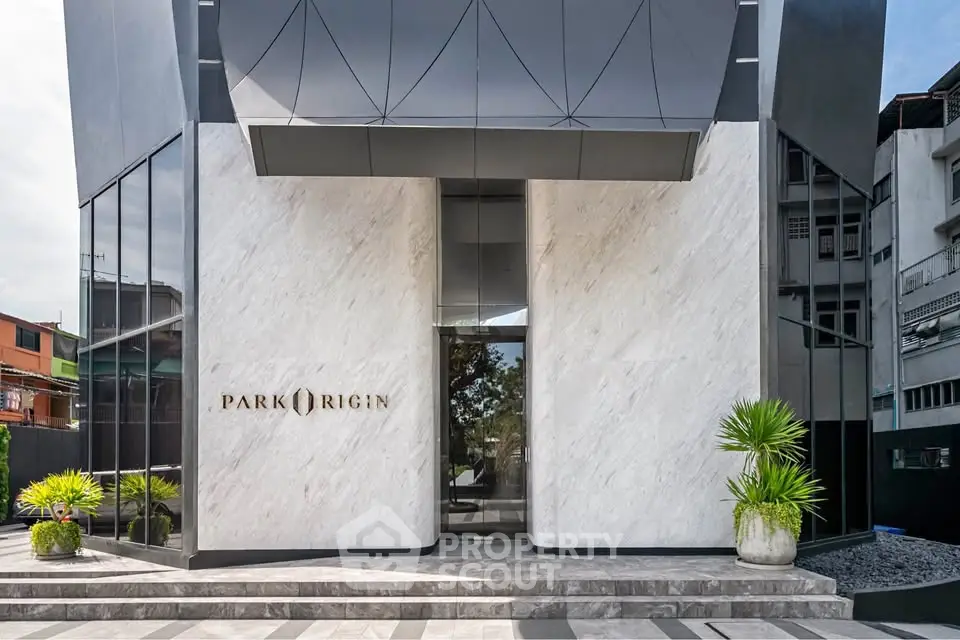 Modern building entrance with sleek design and marble facade, showcasing luxury real estate.