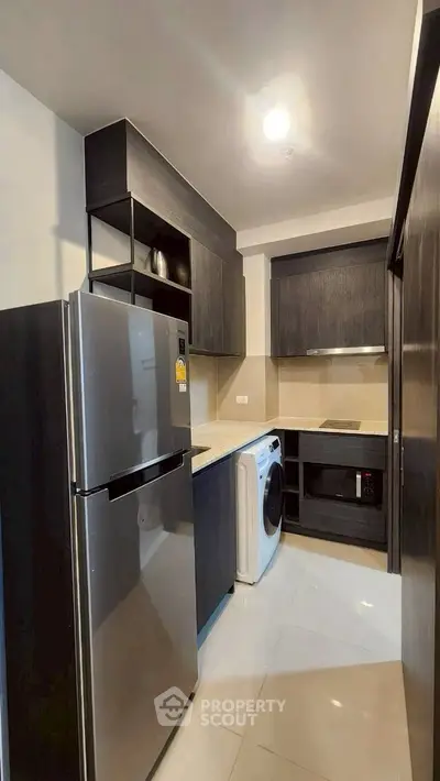 Modern kitchen with sleek black cabinets, stainless steel fridge, and built-in appliances.