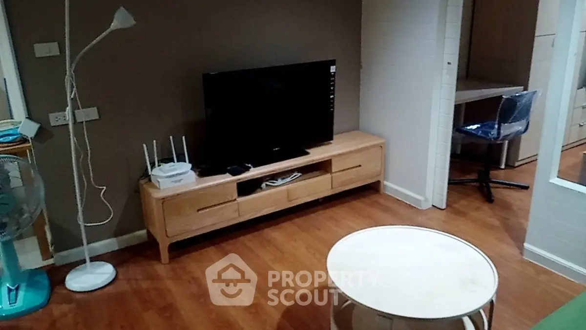 Cozy living room with modern TV setup and stylish wooden furniture, perfect for relaxation.