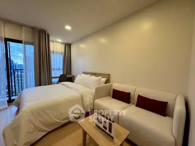 Modern studio apartment with cozy bed and stylish sofa, featuring a city view from the balcony.