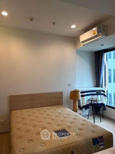 Modern bedroom with large window and air conditioning in urban apartment