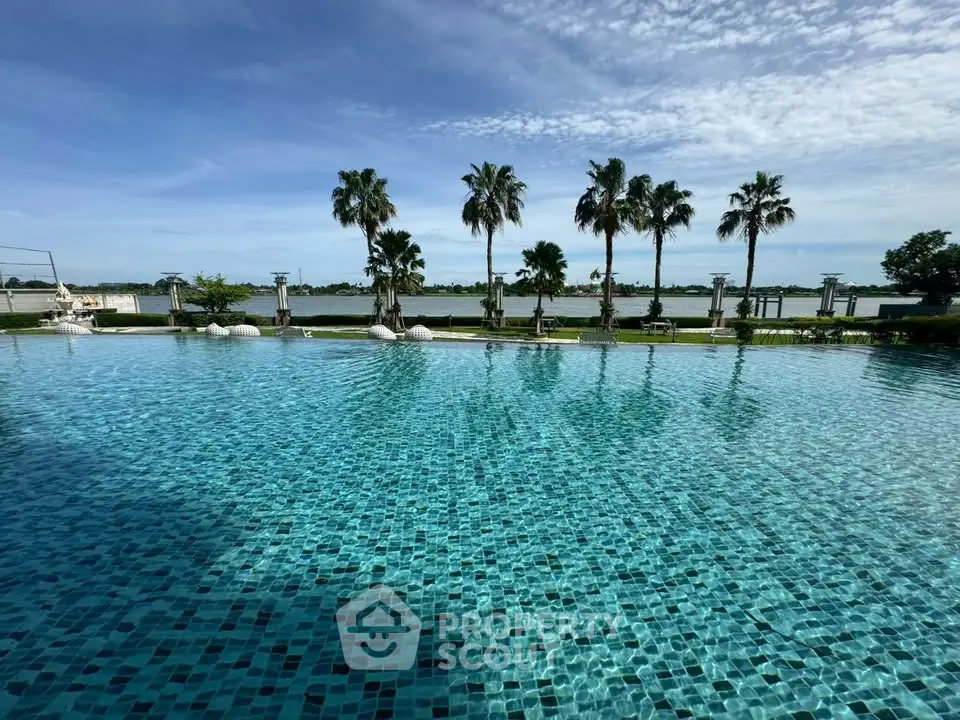 Luxurious poolside view with palm trees and serene water backdrop, perfect for relaxation and leisure.