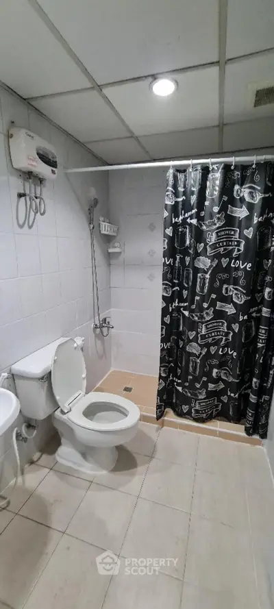 Modern bathroom with shower curtain and white fixtures in a tiled setting.