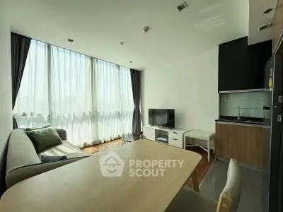 Modern living room with large windows and compact kitchen in open layout apartment.