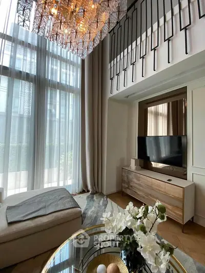 Luxurious living room with high ceilings, elegant chandelier, and modern decor in a stylish apartment.