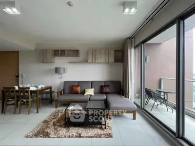 Modern living room with large glass doors leading to a balcony, featuring stylish furniture and dining area.
