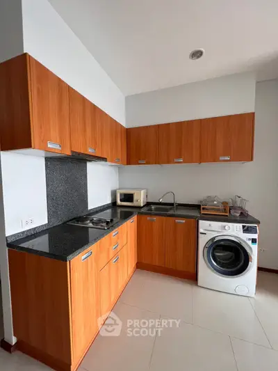 Modern kitchen with wooden cabinets, granite countertops, and built-in washing machine