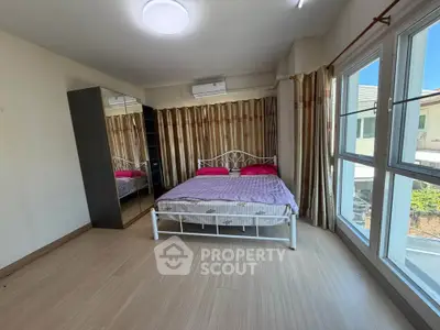 Spacious bedroom with large windows and modern decor in a well-lit apartment.