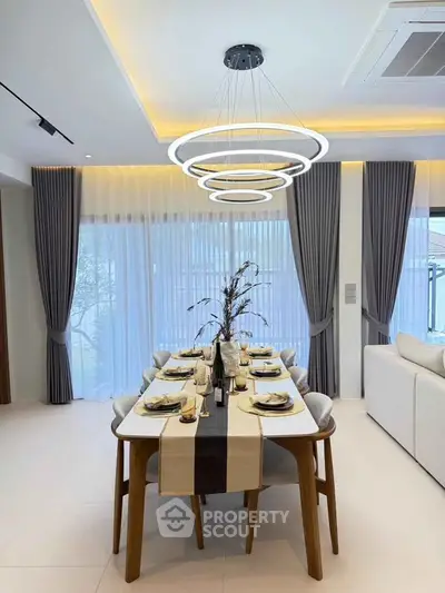 Elegant dining room with modern chandelier and stylish table setting in a luxurious home.