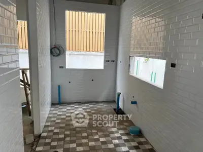 Under-construction bathroom with tiled walls and floor, plumbing fixtures visible.