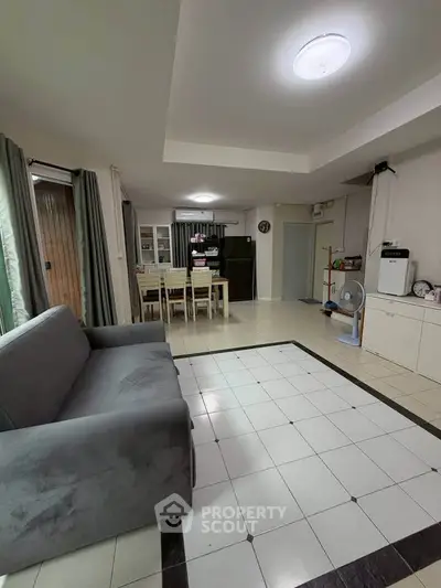Spacious living room with modern furniture and tiled flooring, perfect for family gatherings.